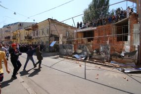 Participants of the rally demolish the building near the house with one wall