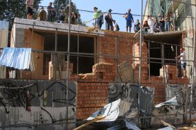 Participants of the rally demolish the building near the house with one wall