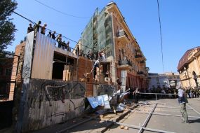 Participants of the rally demolish the building near the house with one wall