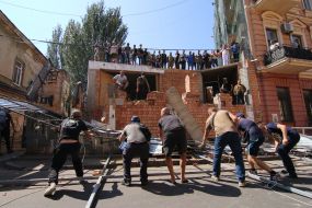 Participants of the rally demolish the building near the house with one wall