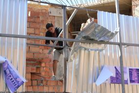 Participants of the rally demolish the building near the house with one wall