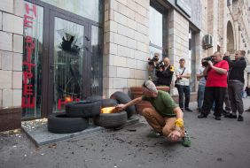 Activist is trying to set fire to the tire near the store "Emporium"