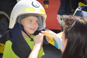 A woman buttoning a rescuer's helmet on the child
