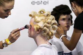 Визажист наносит макияж модели