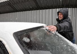 Мужчина убирает снег с машины