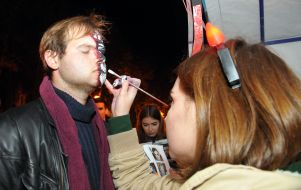 The girl draws a mask on the man's face