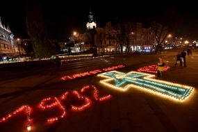 Крест и цифры, выложенные из зажженных лампадок