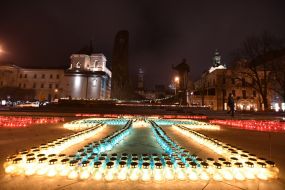 Крест и цифры, выложенные из зажженных лампадок