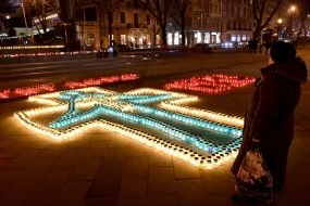 Крест и цифры, выложенные из зажженных лампадок