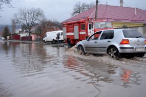 The car is driving through a flooded street