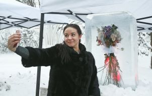 The girl makes a sephi on the background of the ice sculpture