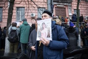 The man is holding a leaflet with the image of Irina Nozdrovskaya