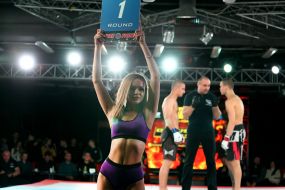 The girl holds the plate with the number of the battle round