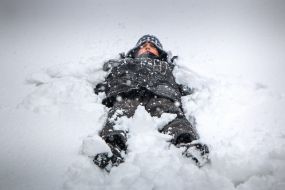 The boy lies in the snow