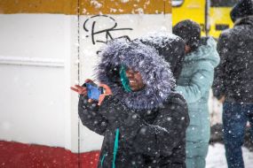 A woman photographing a snowball on her mobile phone
