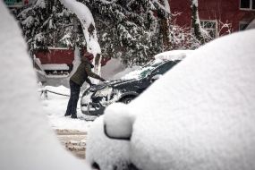 Woman cleans the car from snow