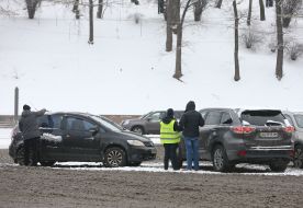 Мужчина счищает снег с автомобиля