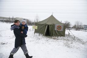 Жінка з дитиною на руках проходить біля пункту обігріву