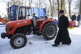 Священнослужитель  проходит возле снегоуборочной техники