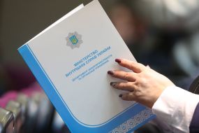 Участница годовой итоговой коллегии МВД держит папку