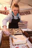 Учасниця виставки-ярмарки відрізає шматок випічки