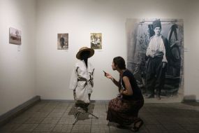 A girl with a phone examines a mannequin