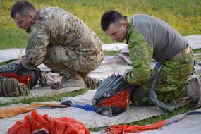 Military personnel fold parachutes before jumping