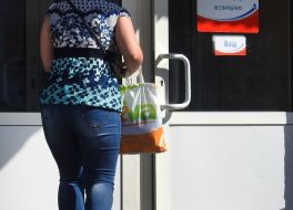 Женщина заходит в магазин с полиэтиленовым пакетом