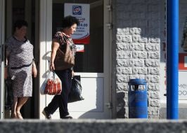 Женщина выходит из магазина с полиэтиленовым пакетом