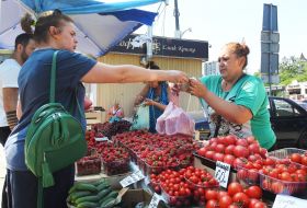 Продавец передает покупателю клубнику в полиэтиленовом пакете
