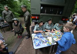 A girl in medical uniform examines a dogChildren near the military