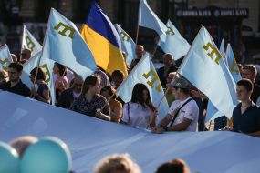 Люди тримають національний прапор кримських татар