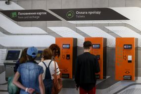 Пассажиры используют автомат по продаже жетонов