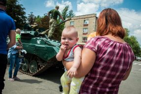 A woman with a child at an exhibition of military equipment