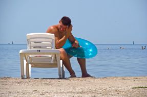 Мужчина сидит на шезлонге с надувным кругом