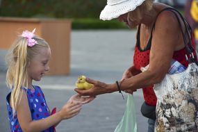 The woman gives the girl a duckling