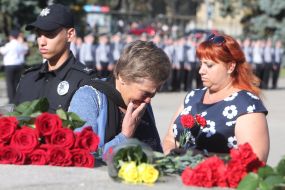 Women put bouquets on the memorial plates
