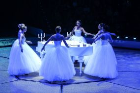 Dancers near the white piano at the circus arena