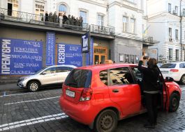 A woman photographs actors on the balcony of the building of the Young Theater
