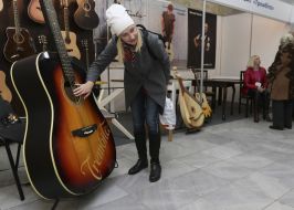 Женщина рассматривает огромную гитару