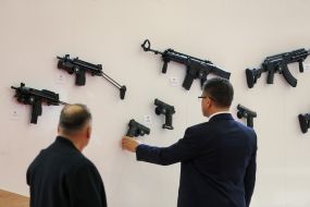 The man looks at the gun on the stand with a gun