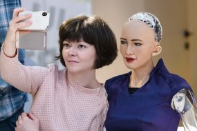 A woman is photographed with a robot Sophia