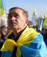 Participant of Prayer for Ukraine with a flag on his shoulders