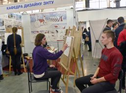 Участник ярмарки образования пишет портрет