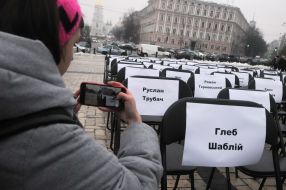 Девушка фотографирует пустые стулья с именами заключенных и пленных