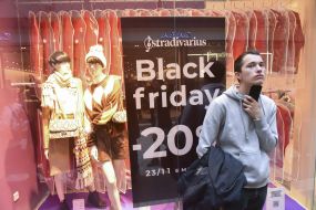 Парень у витрины с объявлением о скидках в "черную пятницу"