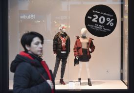 Женщина у витрины с объявлением о скидках в "черную пятницу"