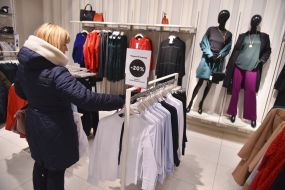 Женщина выбирает блузку в магазине в "черную пятницу"