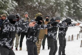 Участники подготовки Национальных дружин стреляют из пистолетов на полигоне