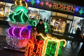 A woman with a child are photographed against the backdrop of a New Year's installation